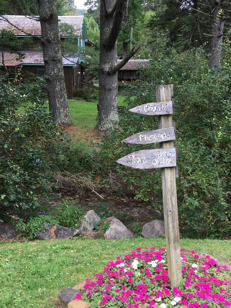Hand-made wooden directional sign pointing to church, museum, post office, and store