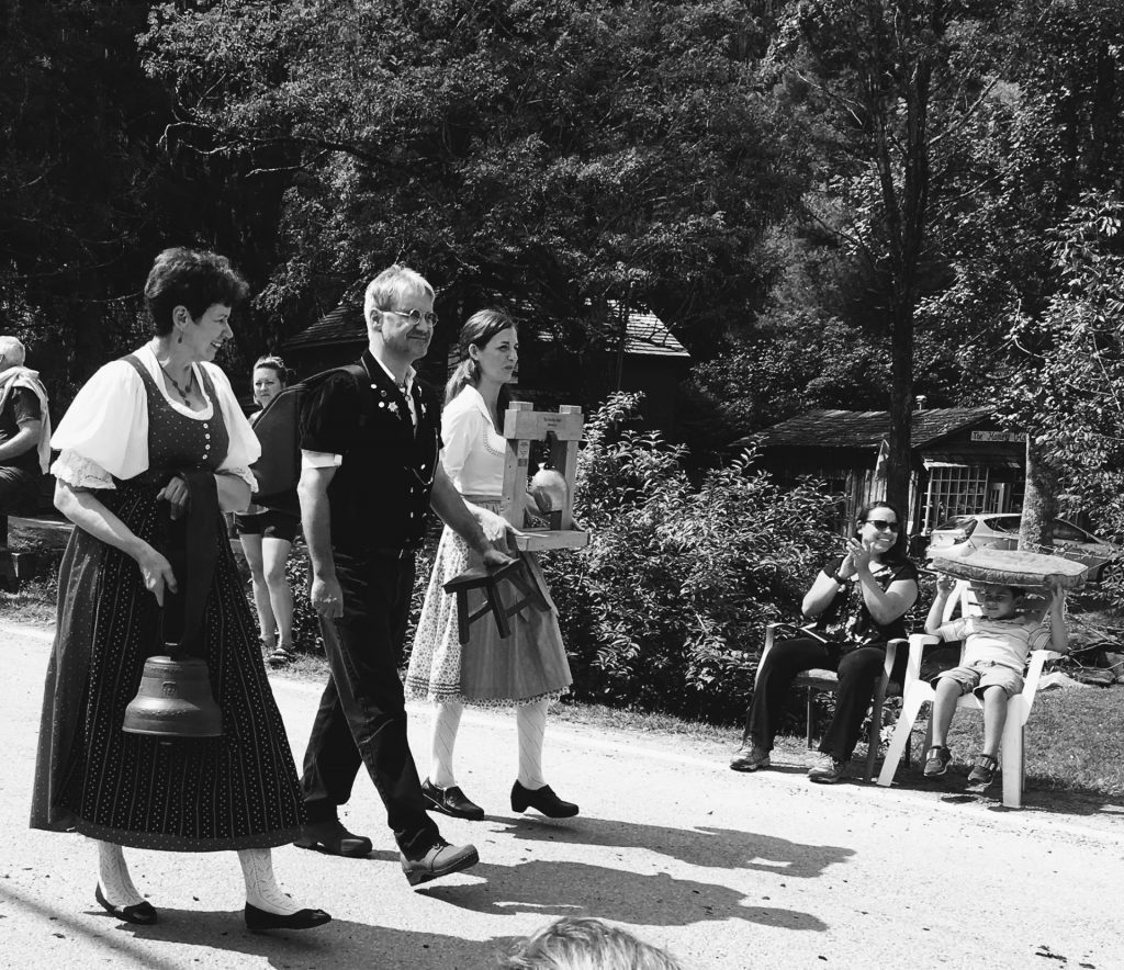 People in traditional Swiss-German dress walking in parade, black and white photograph